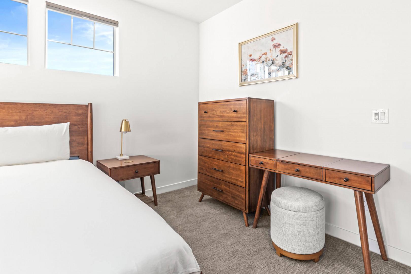 Your bright, serene bedroom features a plush bed, warm wood furniture, and a lovely vanity area where you can start each morning relaxed and refreshed.