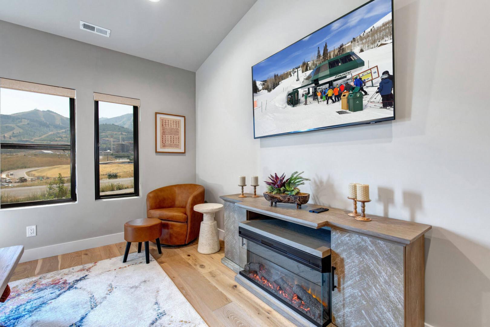 Unwind in your cozy sitting area where mountain vistas frame your view. Natural light floods the space, highlighting warm wood floors and a stylish fireplace perfect for après-ski evenings.