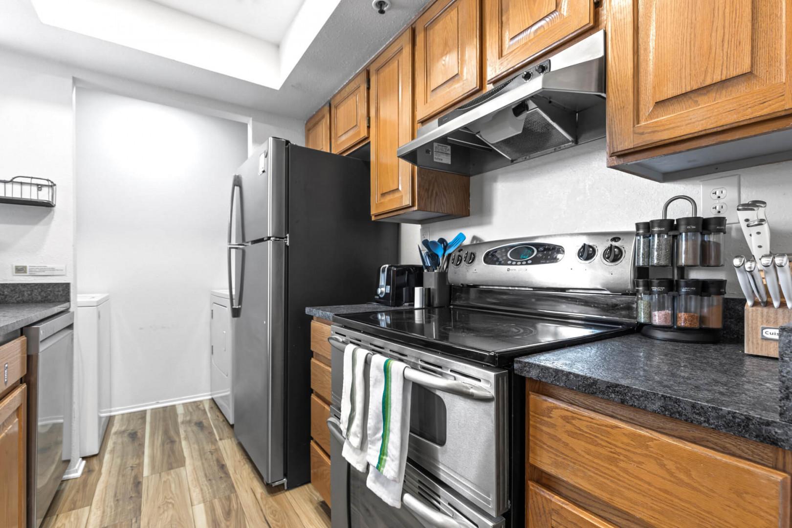 Powderwood 12N- Modern electric range, refrigerator, and sleek kitchen cabinets in vibrant setting.