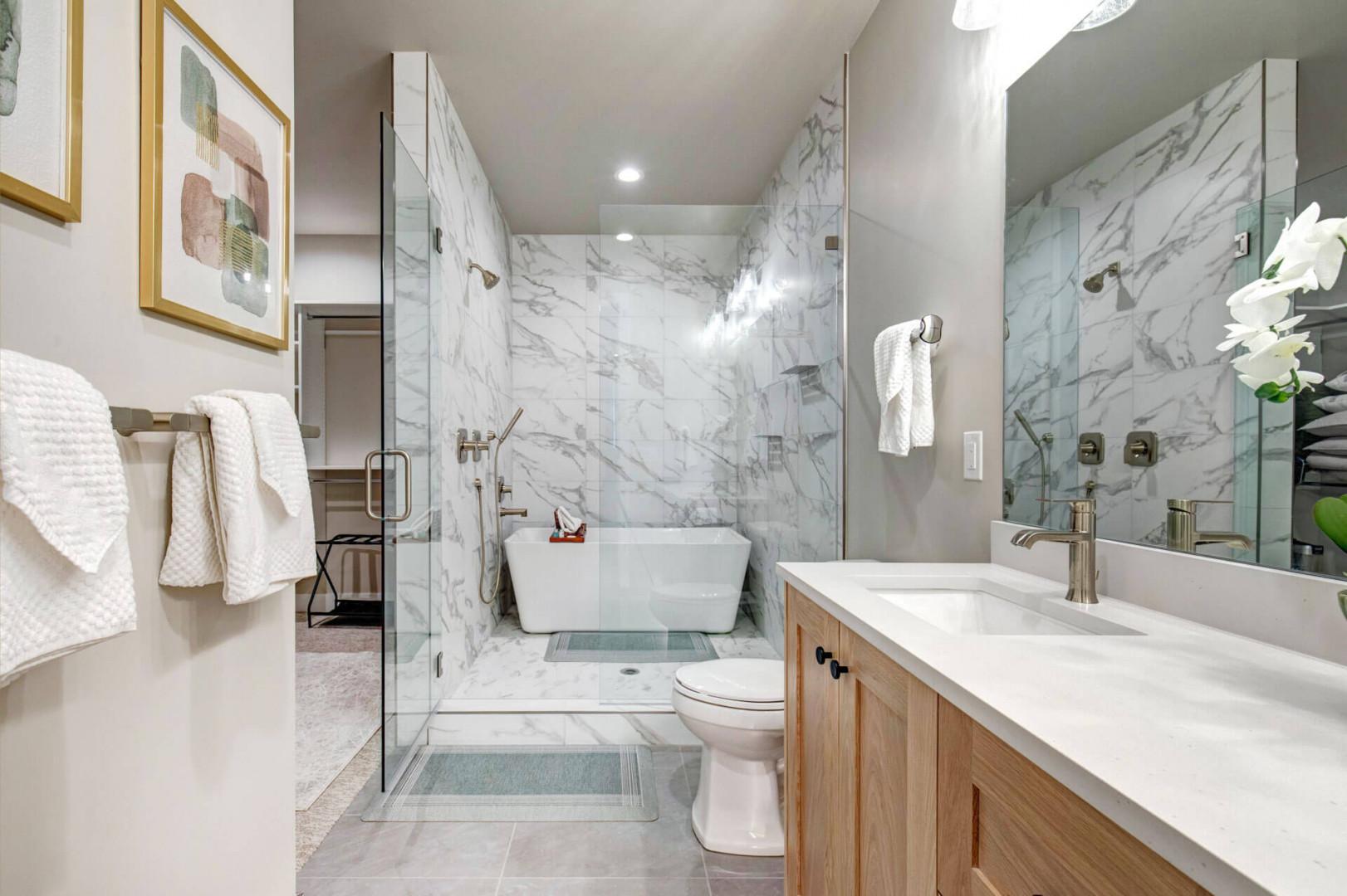 Step into your private spa-like retreat with elegant marble walls, a luxurious soaking tub, and a spacious walk-in shower. Plush towels and fresh orchids await your arrival.