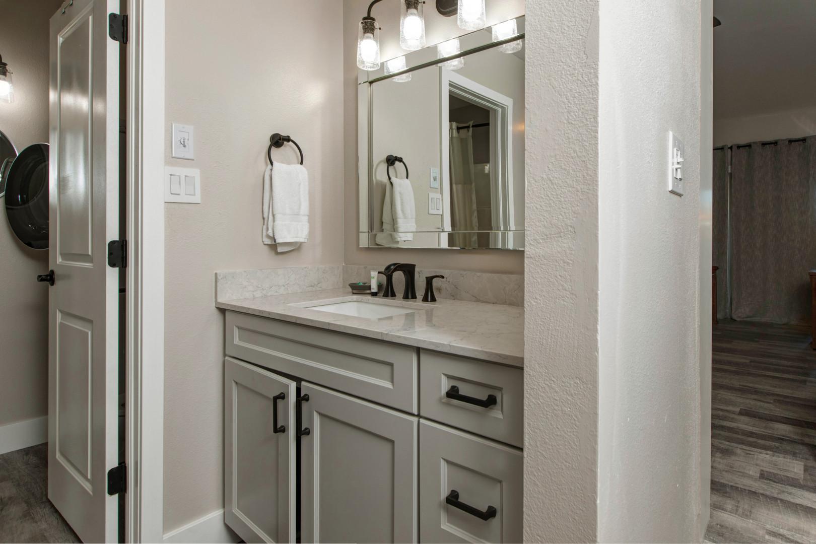 Sleek sink, mirror, cabinets, and overhead lights create a cozy space.