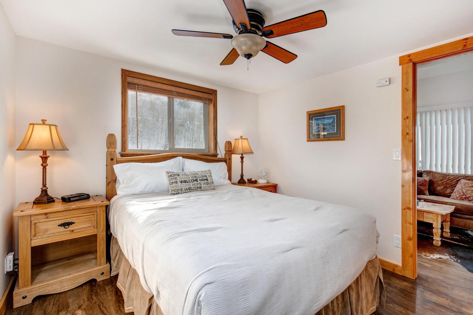 Cozy queen bed with a view, flanked by two lampshades.