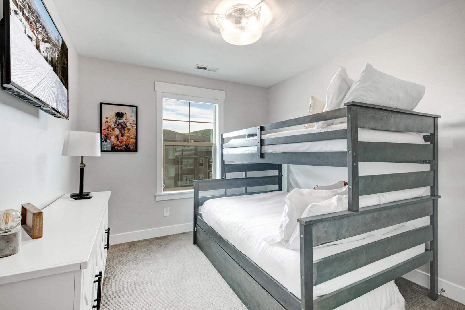 Your cozy bunk room with fresh linens and a bright mountain view through the window—perfect for the kids or extra guests.
