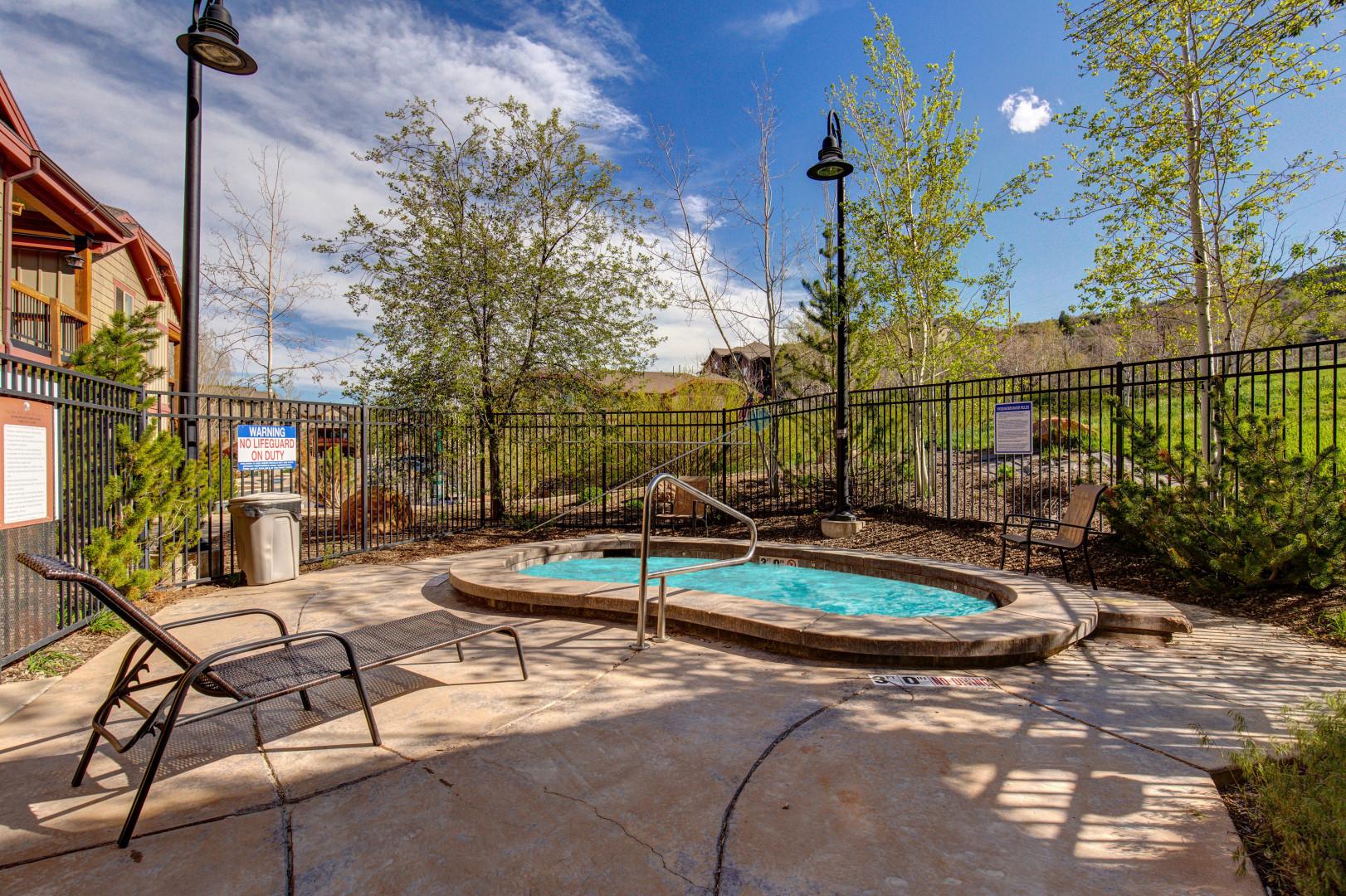 Soak your cares away in this inviting hot tub, perfectly positioned among lush trees for ultimate relaxation.