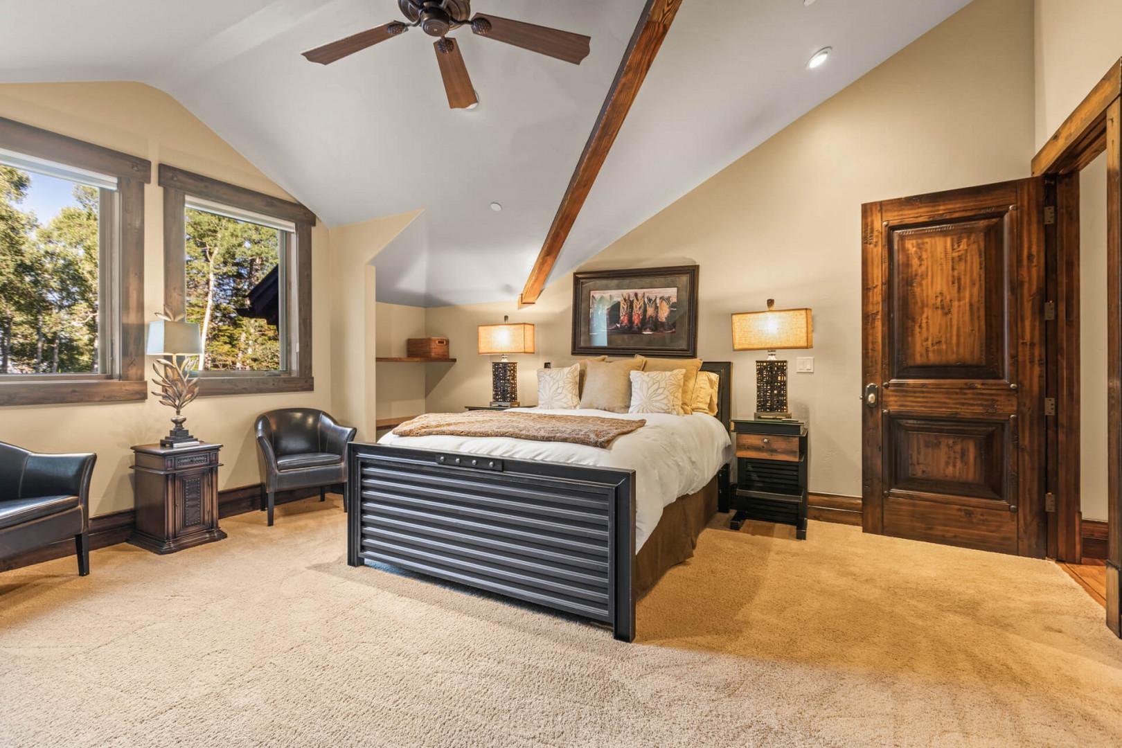 Cozy bed, sofa chairs, and window view in tranquil bedroom.