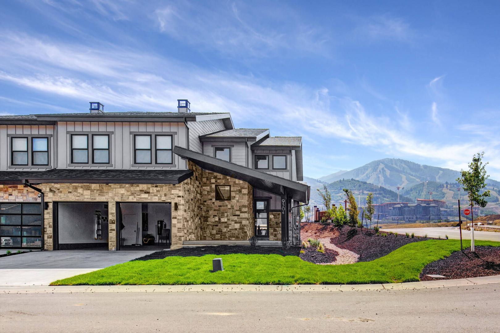 Modern property exterior with mountain backdrop and landscaped grounds, showcasing contemporary design and scenic surroundings.