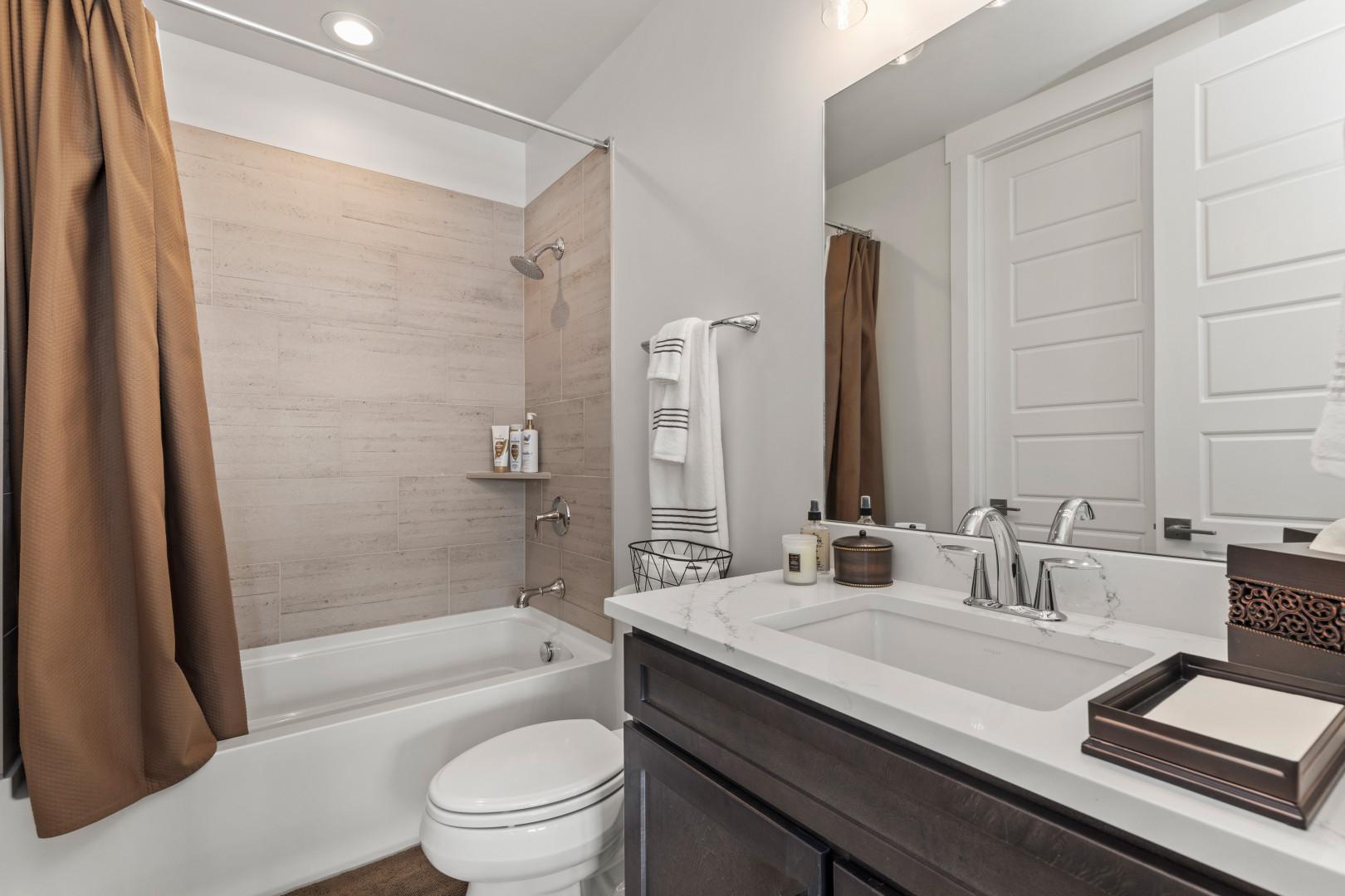 Deer Springs 12797: Sleek sink, mirror, toilet, and convenient tub shower combo.