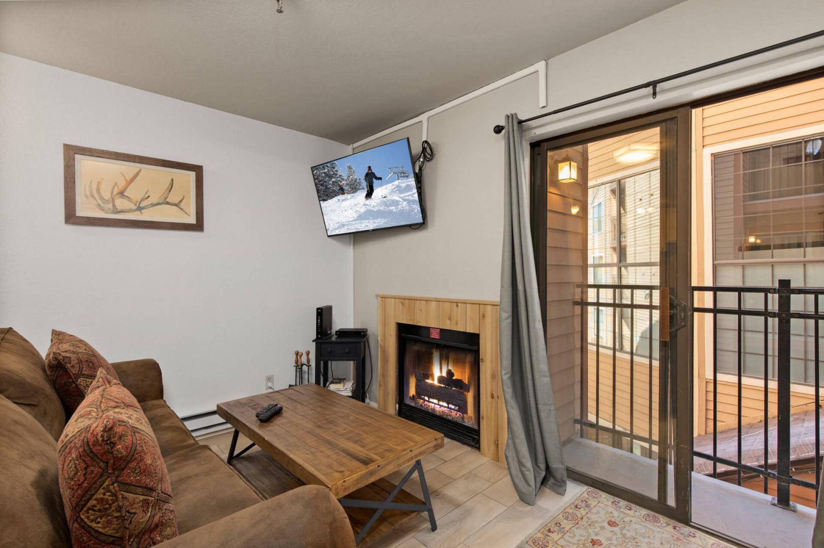 Cozy ambiance with a fireplace and balcony view from the sofa.