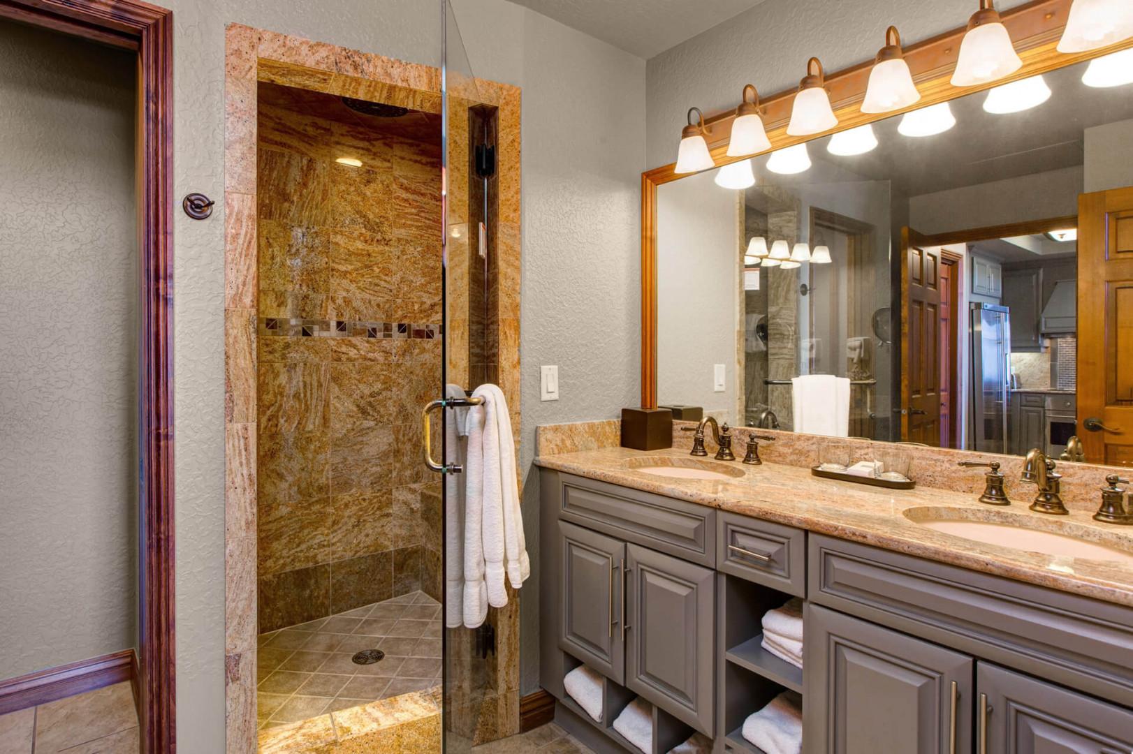 Sleek shower area, illuminated mirror, and modern overhead lights.