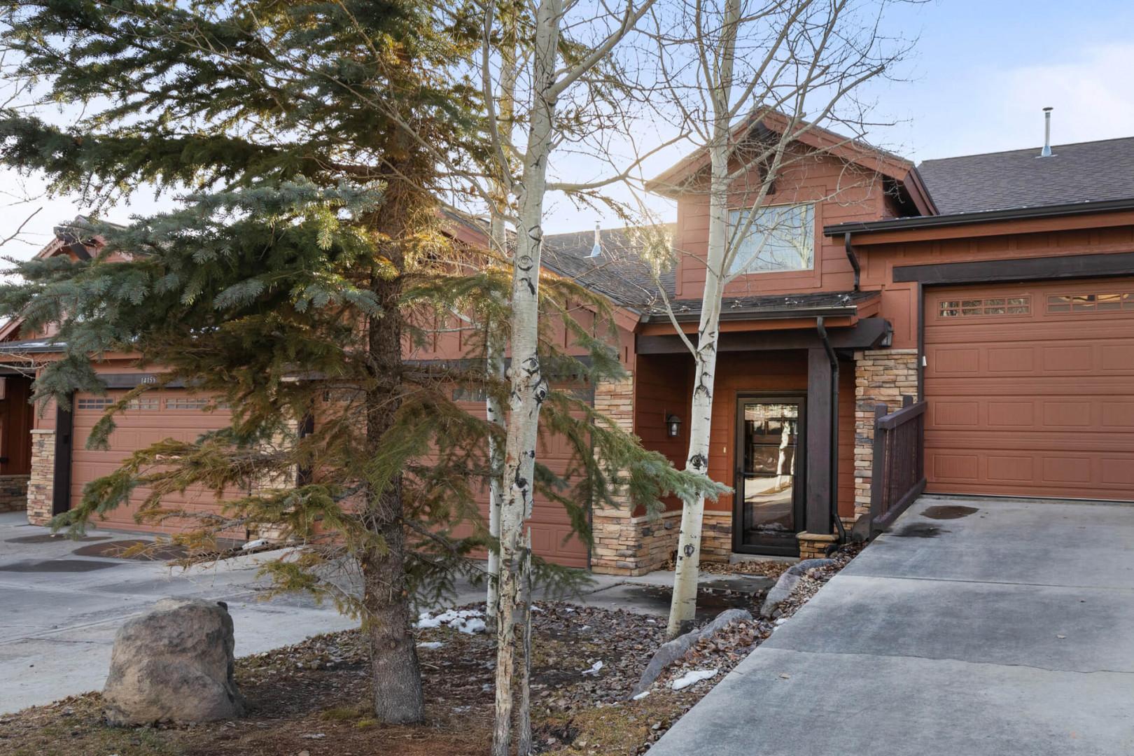 Mountain-style townhomes with stone and wood exteriors provide comfortable lodging surrounded by alpine trees and natural landscaping.
