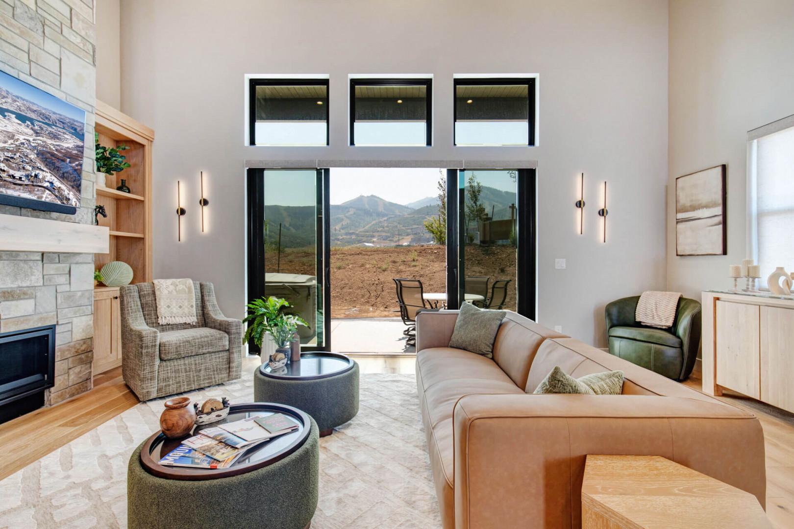 Your bright, modern living room opens to stunning mountain vistas through floor-to-ceiling glass doors, inviting you to relax in stylish comfort while soaking in the natural beauty beyond.