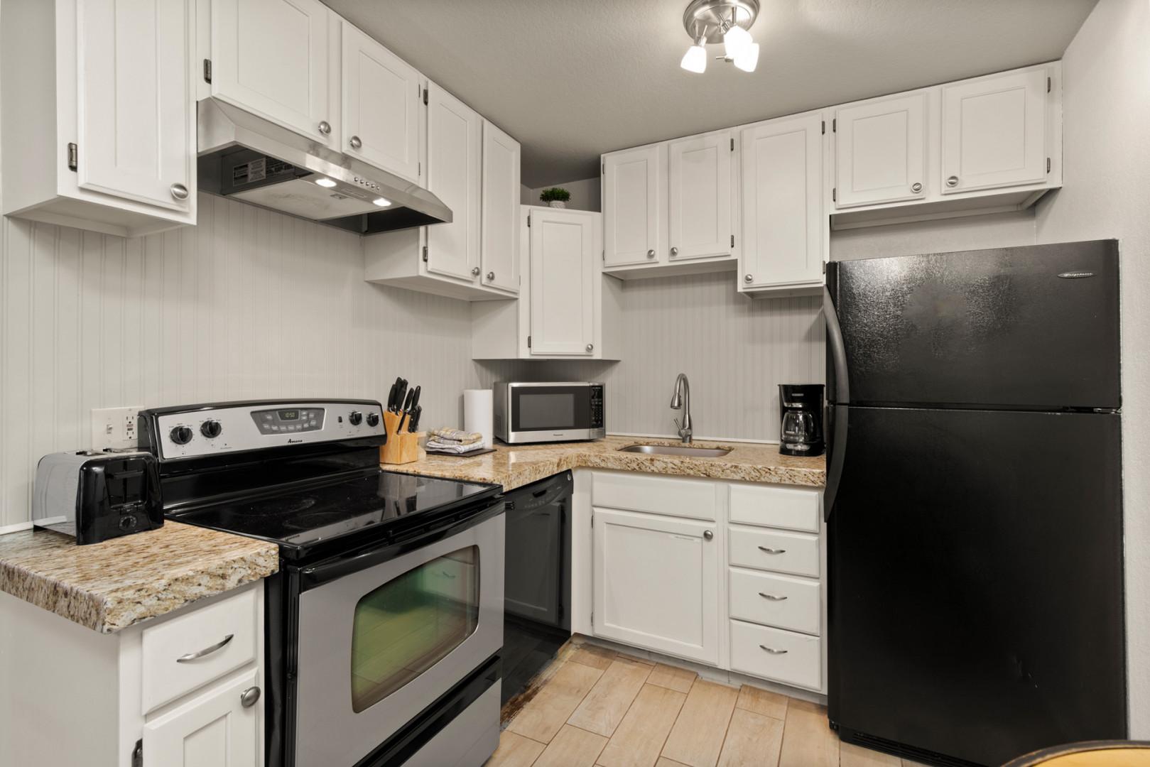 "Equipped with electric range, full-size refrigerator, and modern appliances in cabinets.