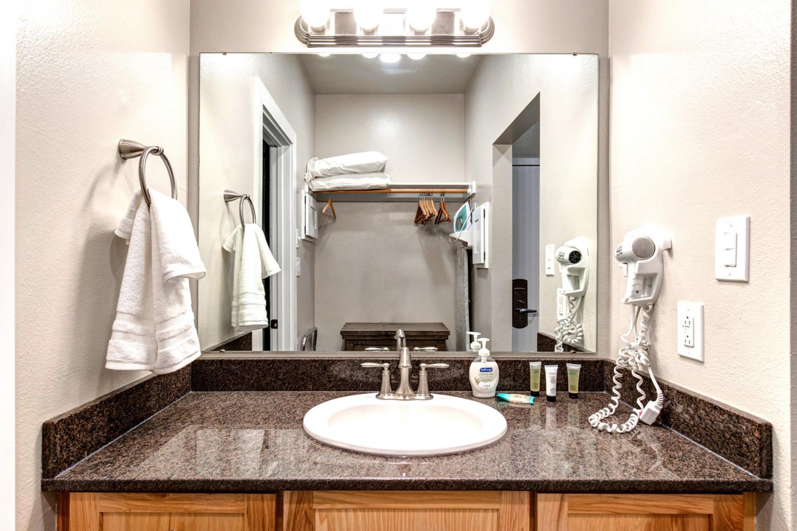 Bathroom: "Sleek sink, hair dryer, and bright overhead lights in modern bathroom."