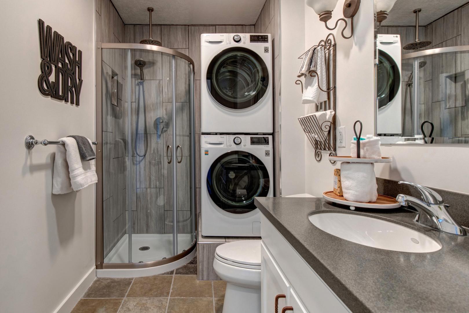 The Mason at Stillwater 7072: Shower, sink, mirror, and washing machine in a tidy space.