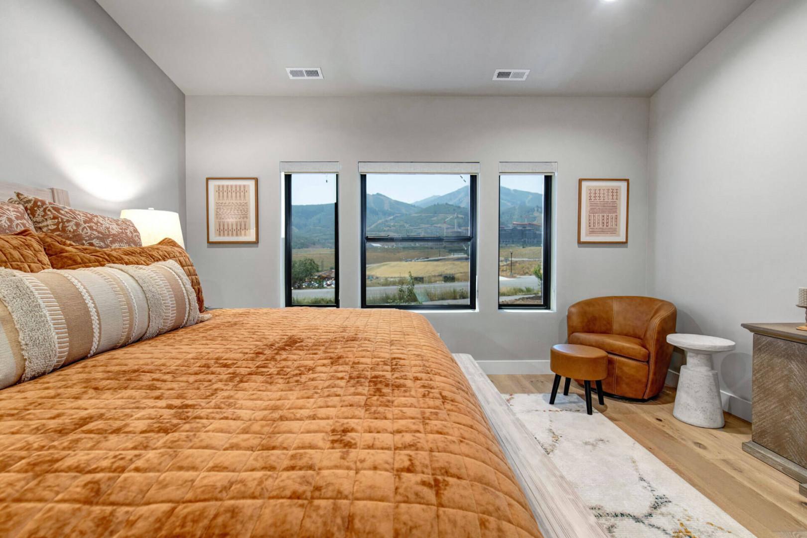 Wake up to breathtaking mountain vistas framed by expansive windows in your serene bedroom retreat. Sink into the plush bedding and unwind in your cozy reading chair as golden hour light fills this peaceful sanctuary.