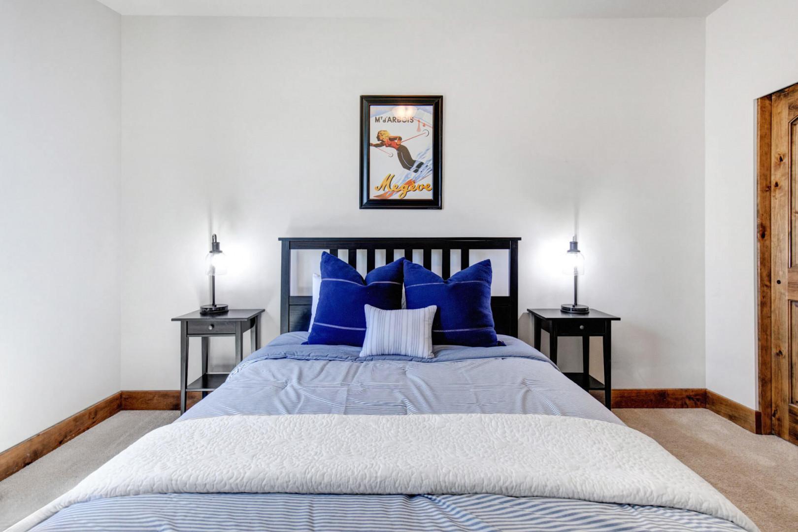 Sink into plush bedding accented with bold blue pillows and soft lighting on either side. Your private retreat awaits with cozy warmth and mountain charm.