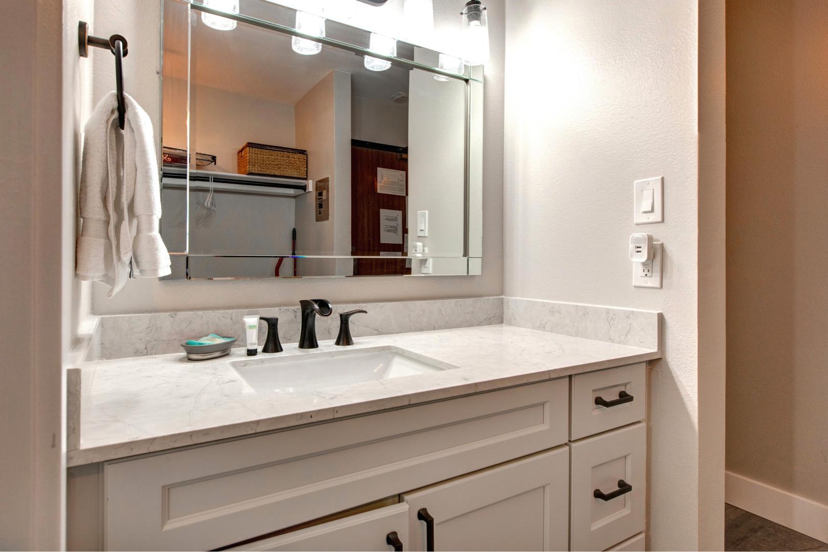 Sleek sink, mirror, cabinets, and overhead lights create a cozy space.