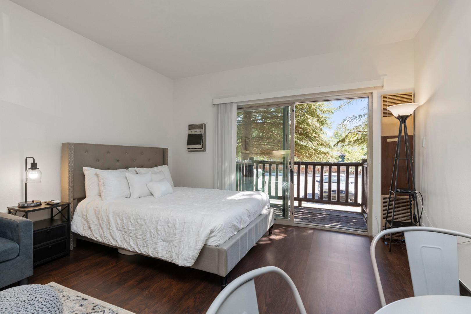 Serene queen bed next to charming outdoor patio, perfect for relaxation.