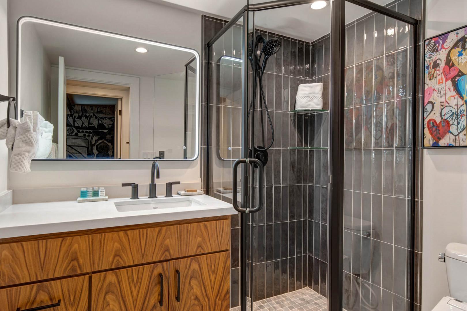 Upper Main 301: Step into your sleek bathroom with stunning dark tile shower and modern vanity—perfect for refreshing after your adventures.