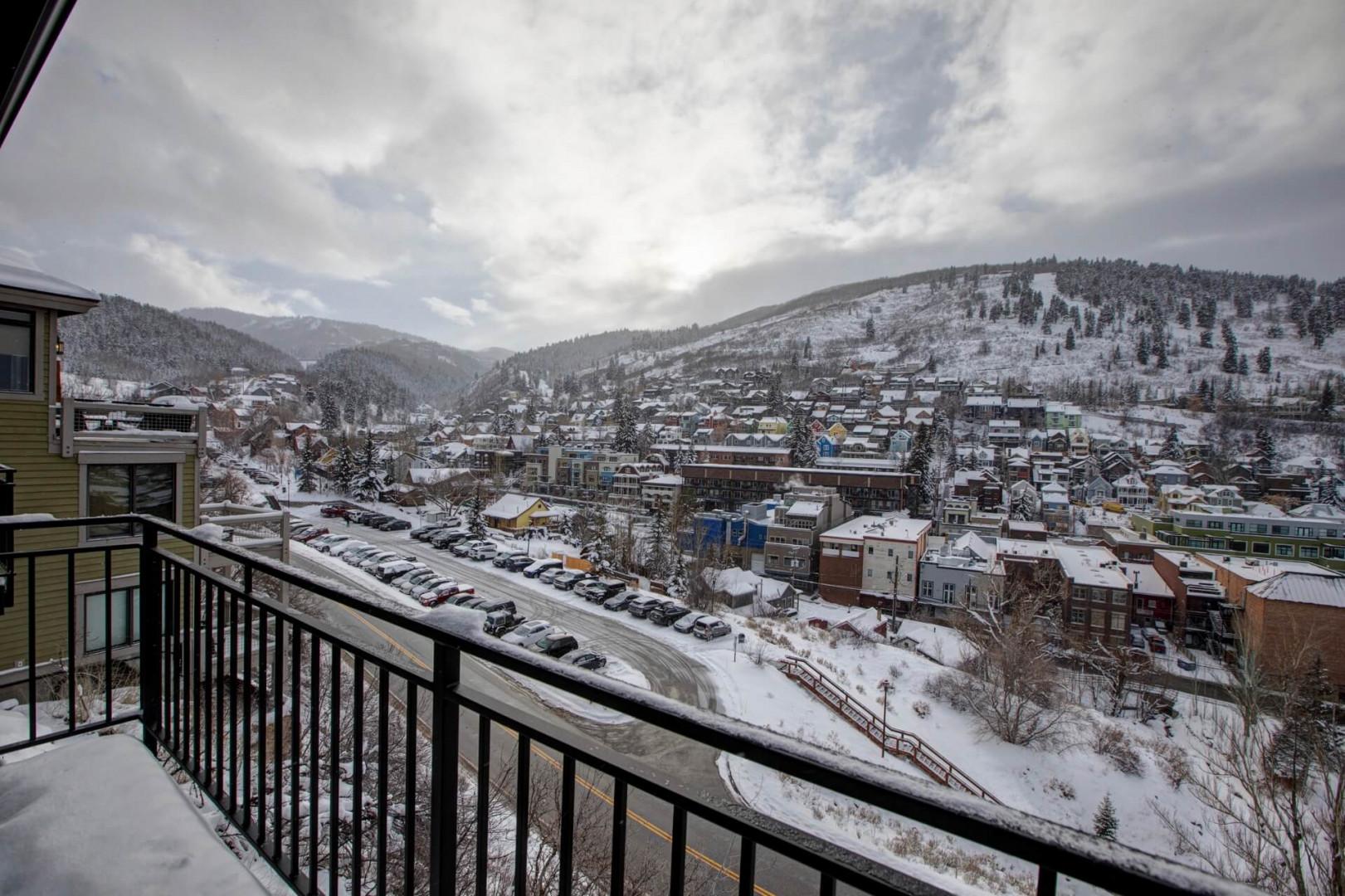 Winter wonderland view showcases snow-covered mountains and charming town below from this elevated balcony vantage point.