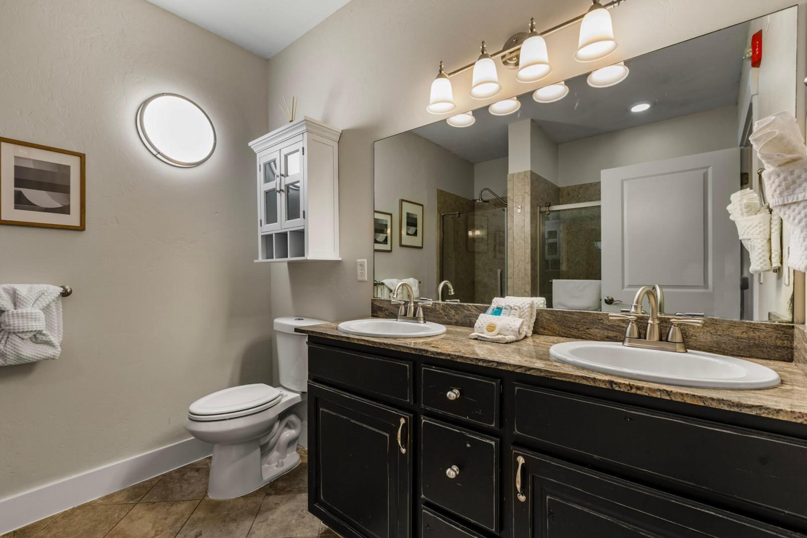 Refresh in your private bathroom featuring dual vanities, elegant granite countertops, modern fixtures, and a walk-in shower—everything you need for a comfortable stay.