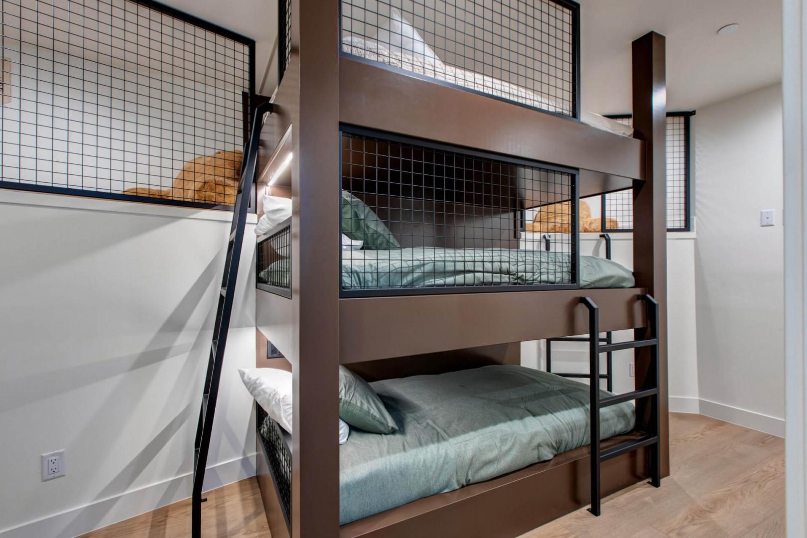 Your stylish bunk room features modern steel-framed beds with cozy teal bedding and safety mesh, perfect for groups or families.