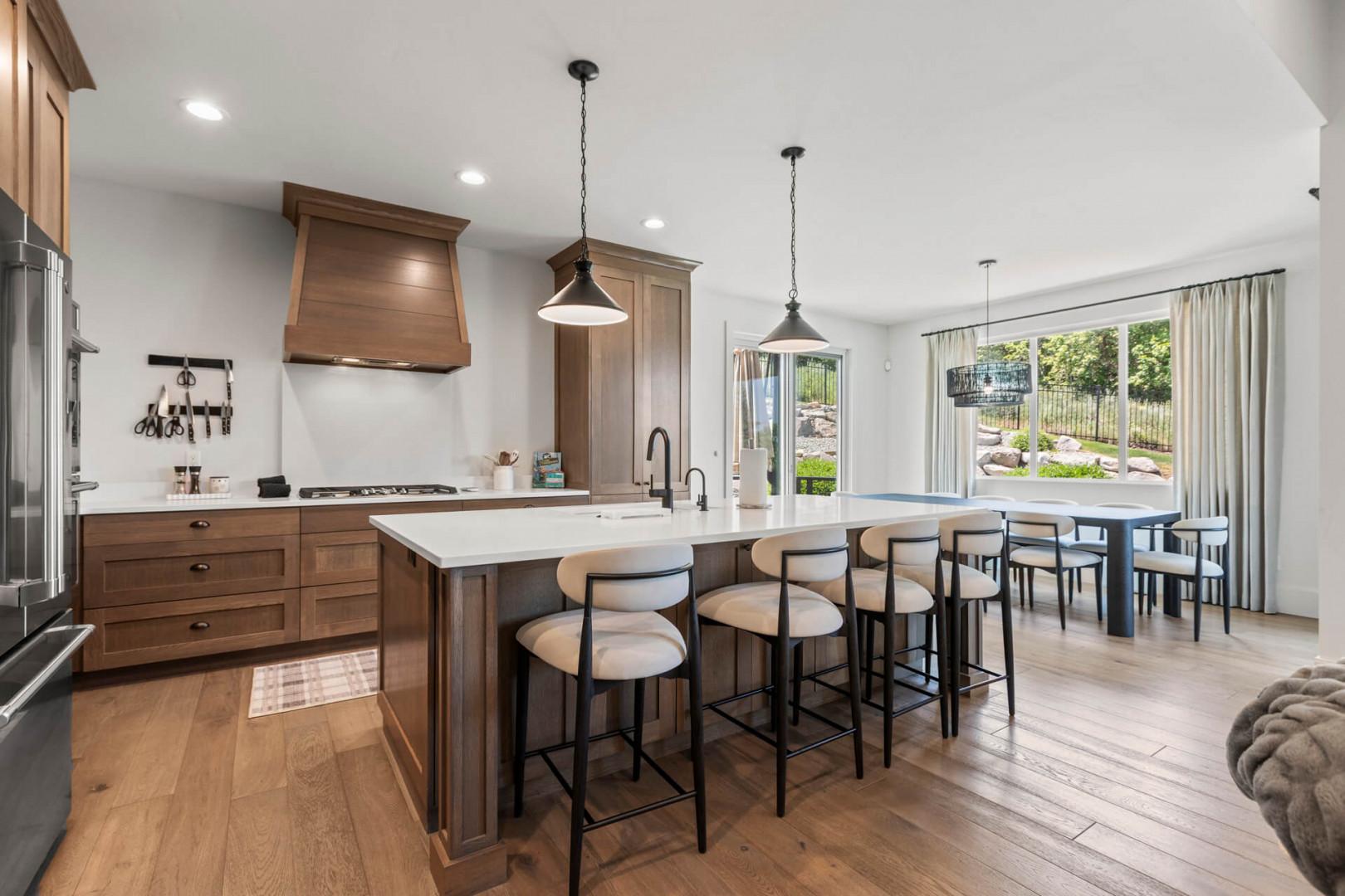 Step into your open-concept kitchen featuring warm wood cabinetry, quartz countertops, and an inviting island with bar seating—perfect for morning coffee or meal prep while chatting with friends and family.