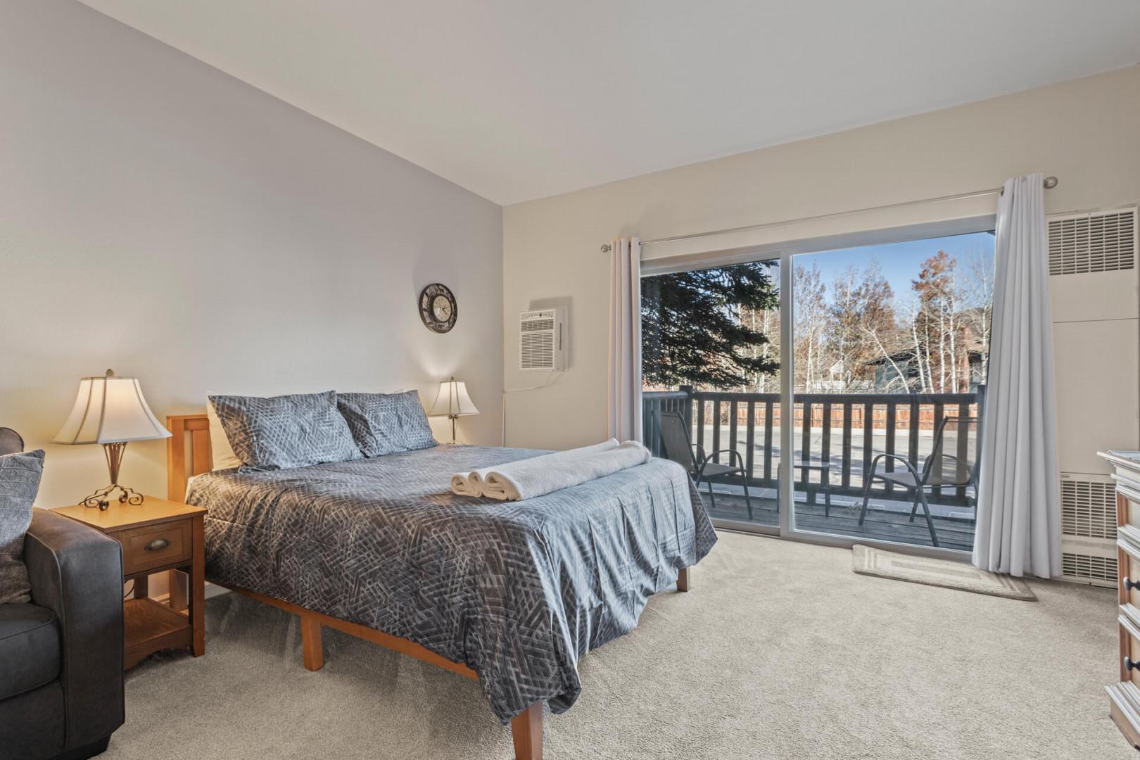 "Serene queen bed next to charming outdoor patio, perfect for relaxation."