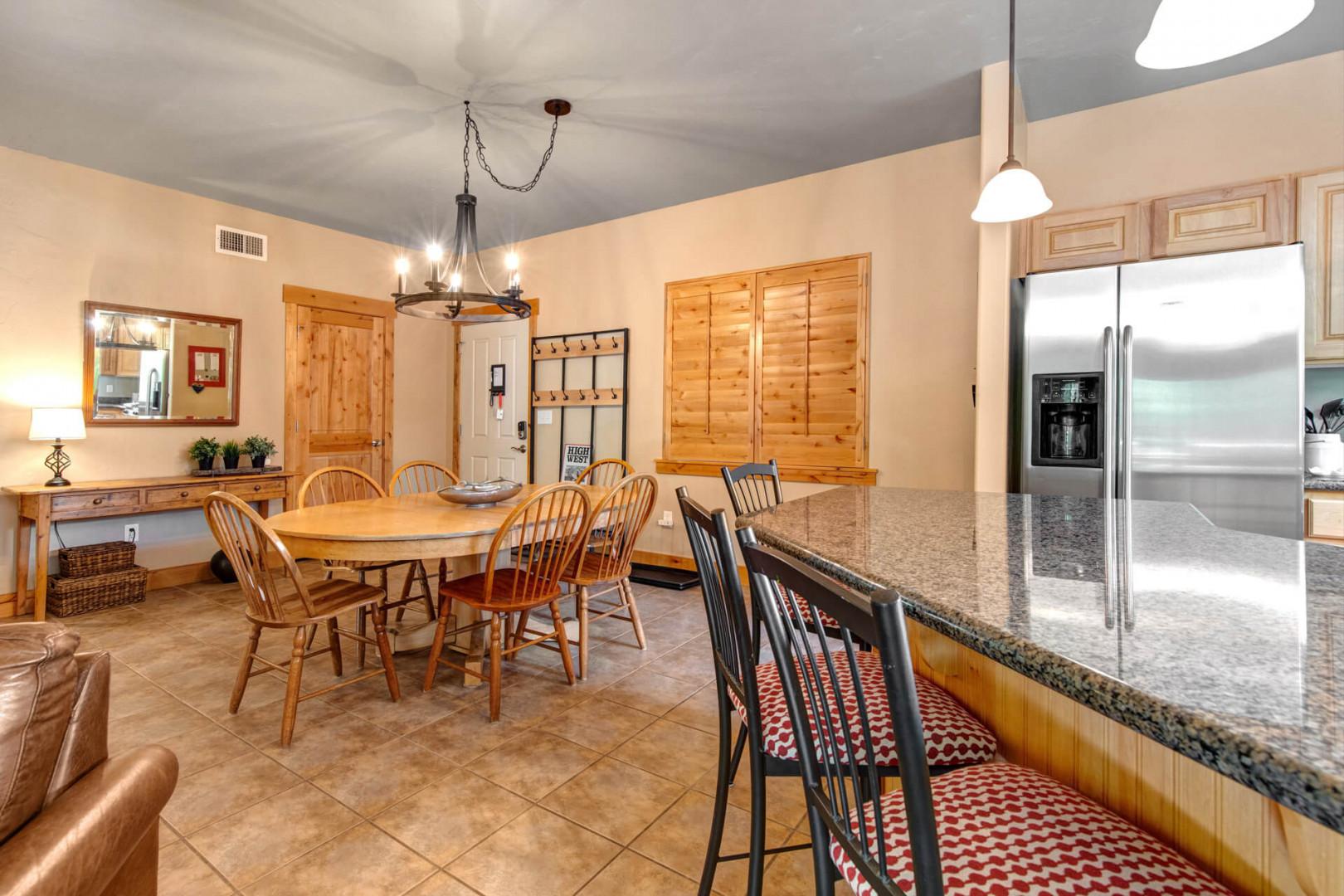 Gather around the warm wood dining table or chat at the kitchen bar with granite counters and modern appliances—your mountain retreat's heart awaits shared meals and memories.