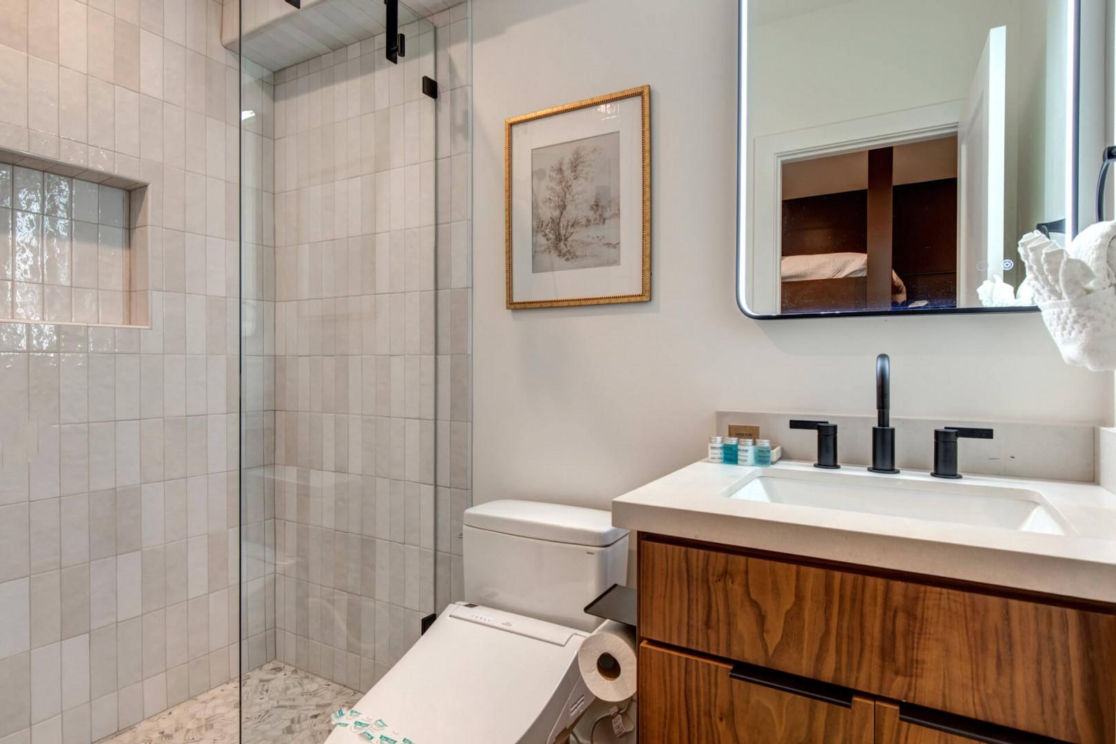 Upper Main 301: Your elegant bathroom features a spacious glass shower, warm wood vanity, and thoughtful amenities for your comfort.