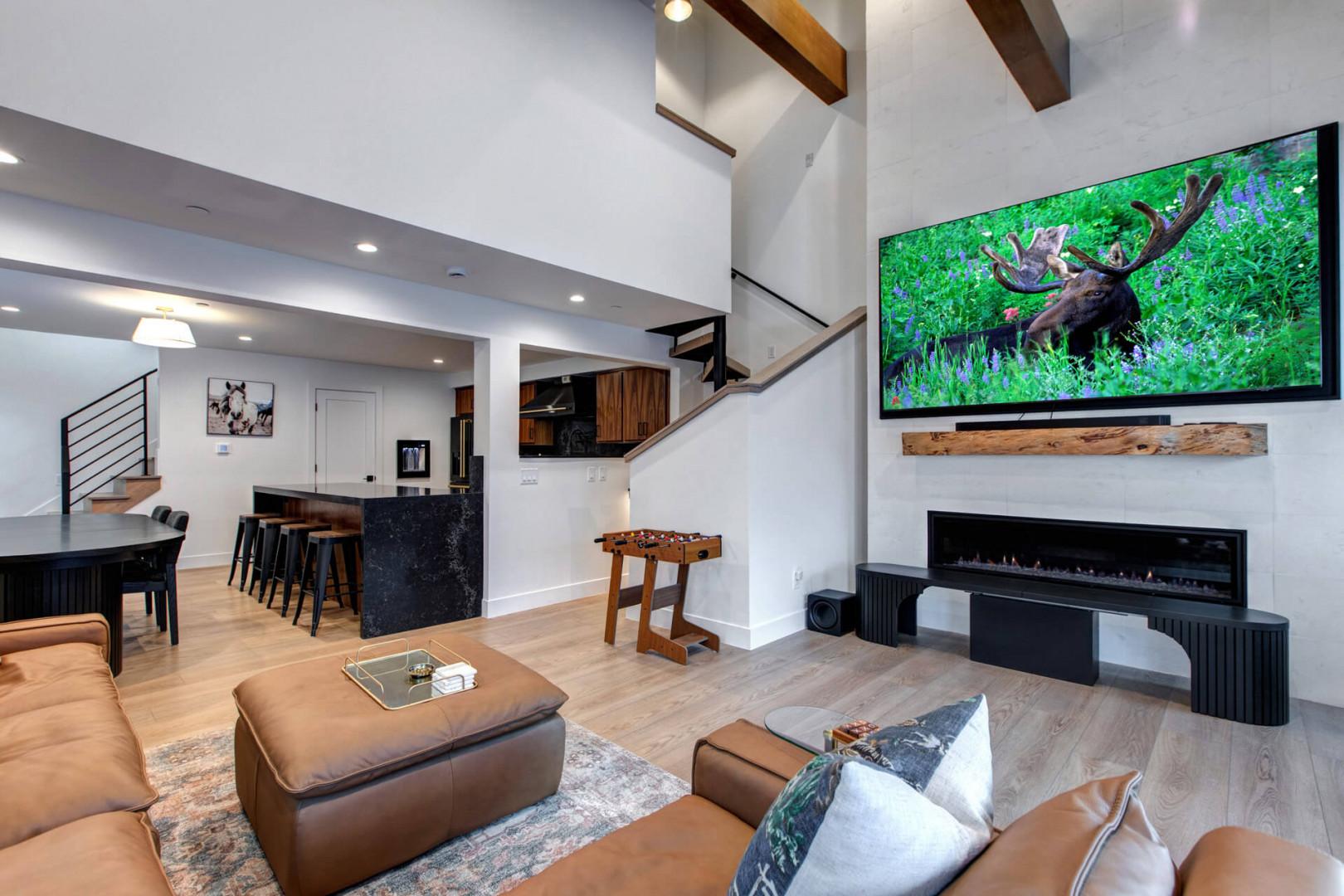 Upper Main 303 Living Room: Relax in your modern living space with soaring beamed ceilings, where your cozy leather seating faces an elegant fireplace and oversized TV.