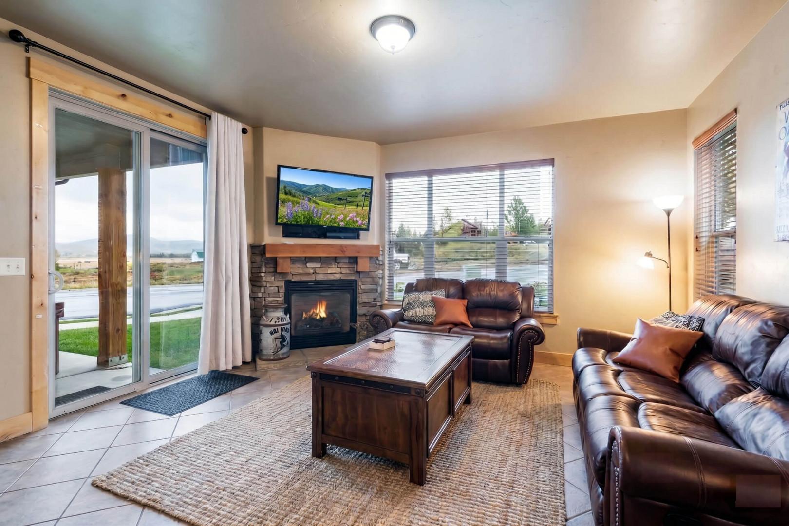 Unwind in your cozy living room with plush leather seating, a warm fireplace, and stunning lake views through expansive windows that frame the natural beauty outside.