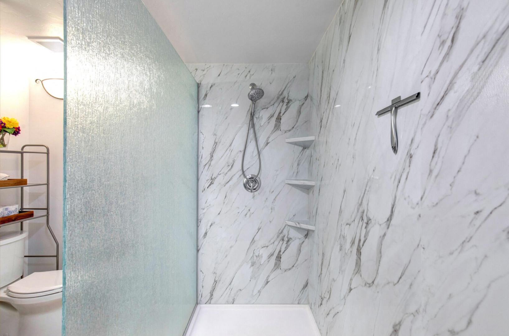 Step into your luxurious marble shower with rainfall head and built-in shelving for ultimate relaxation.