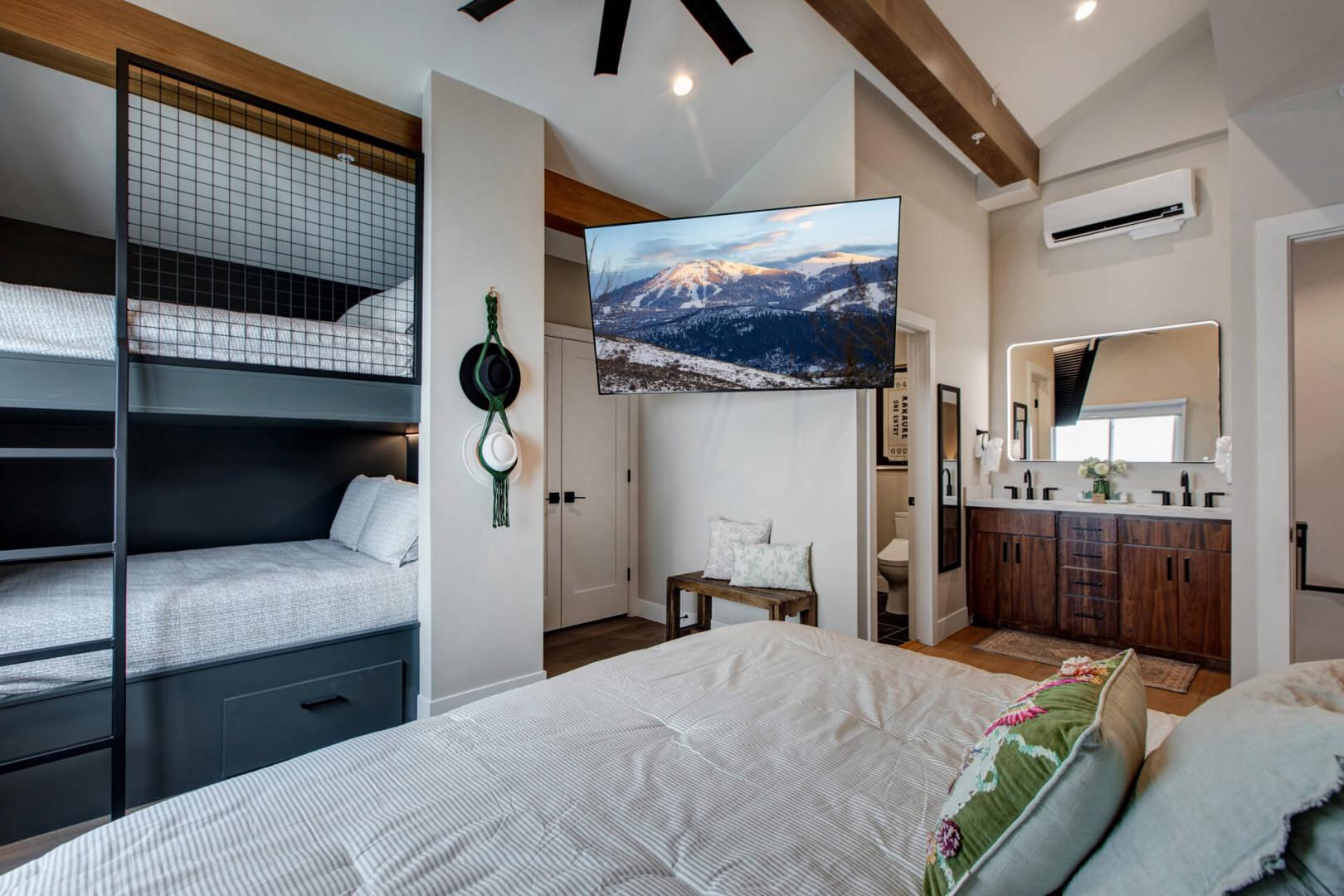 Relax in your mountain-view bedroom featuring cozy bunk beds and modern amenities for the perfect ski retreat.
