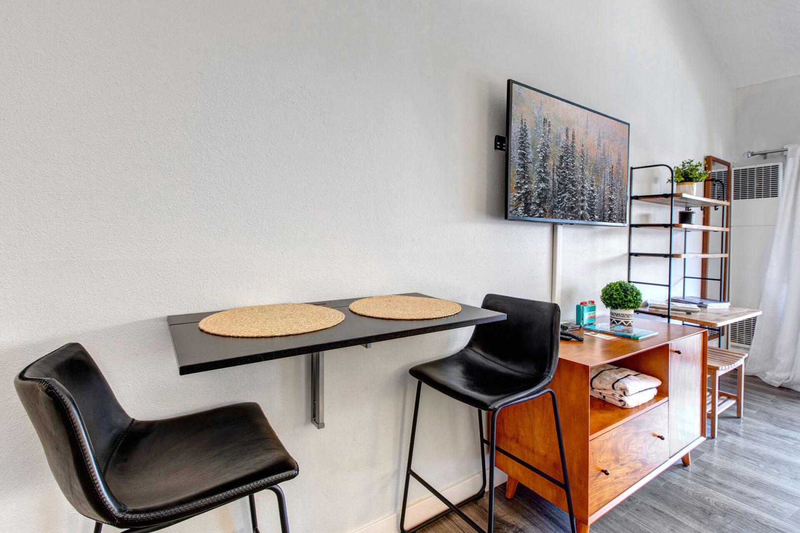 Your sleek dining nook features modern black chairs and a stylish wall-mounted table, perfect for intimate meals or productive work sessions.