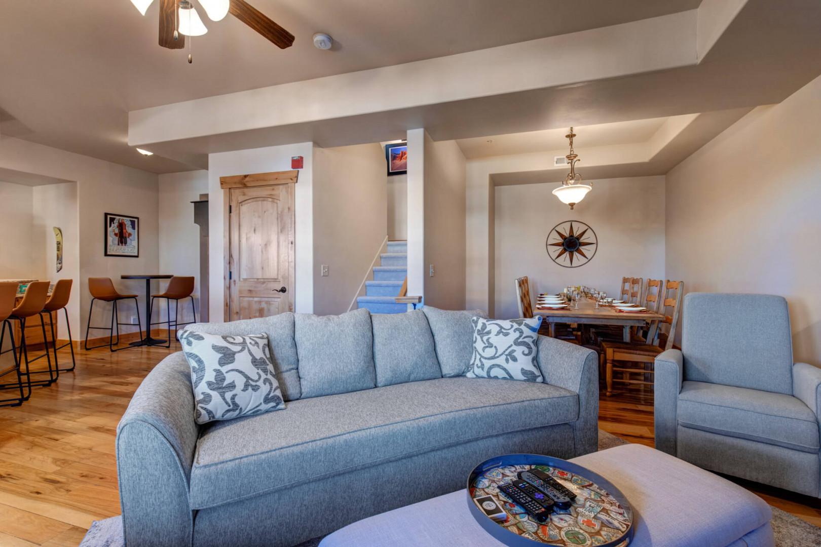 Relax in your spacious living area with plush gray seating and warm wood floors connecting to the dining space.