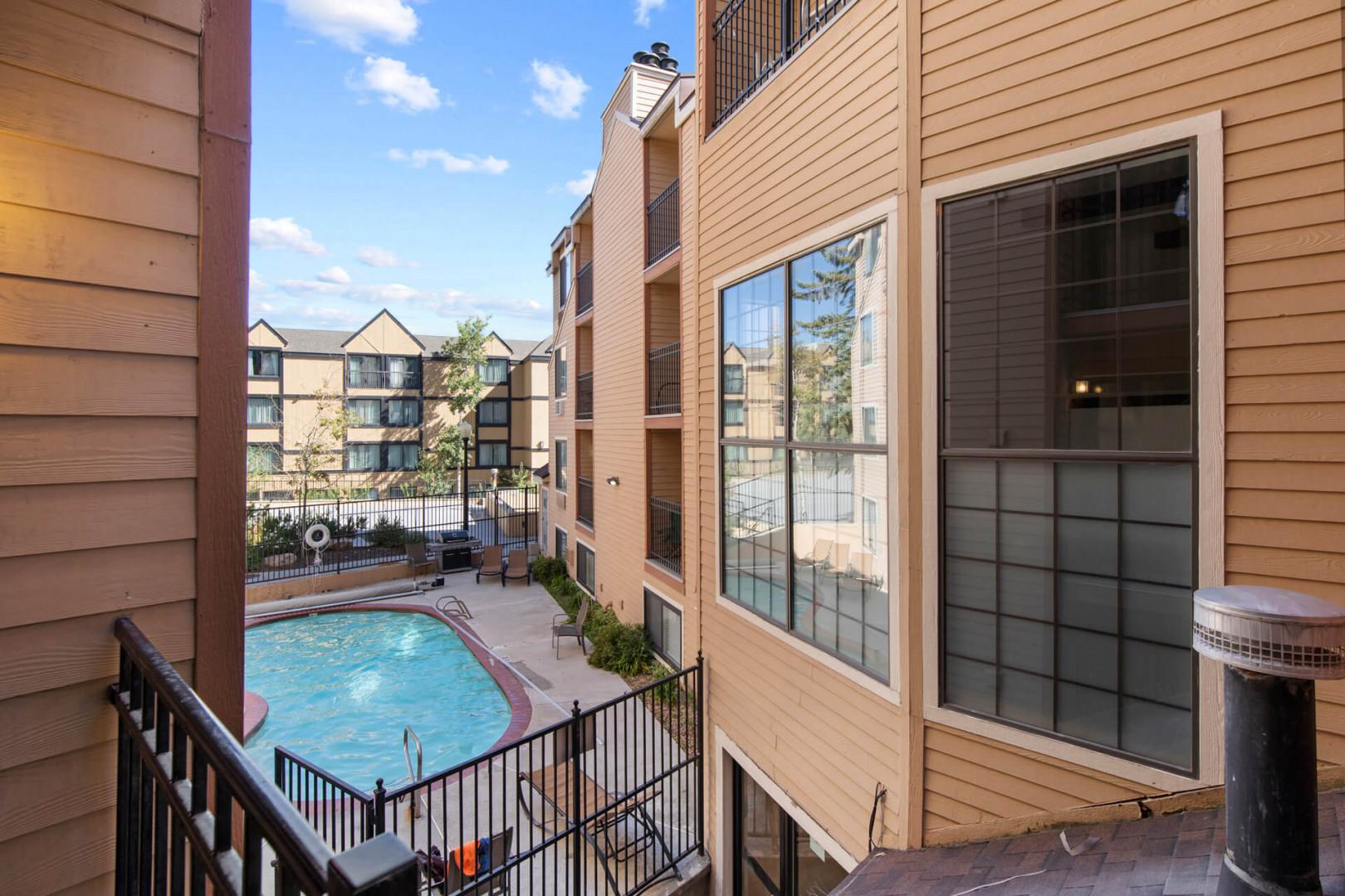 The property features an inviting courtyard area with a pool and hot tub, surrounded by well-maintained buildings and mature landscaping under sunny skies.