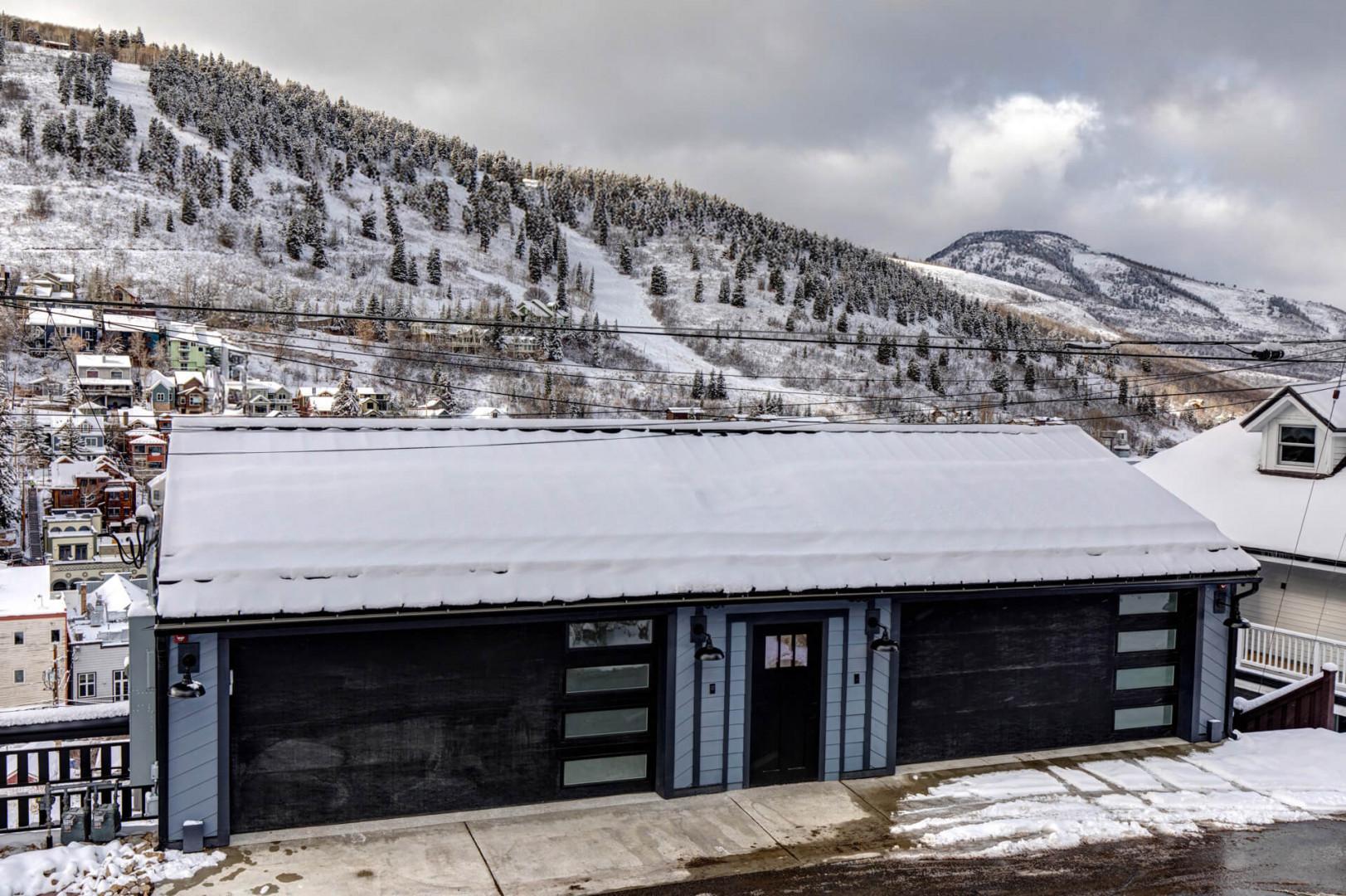 Modern mountain retreat nestled in a snowy alpine valley with ski slopes and scenic mountain peaks surrounding the property.