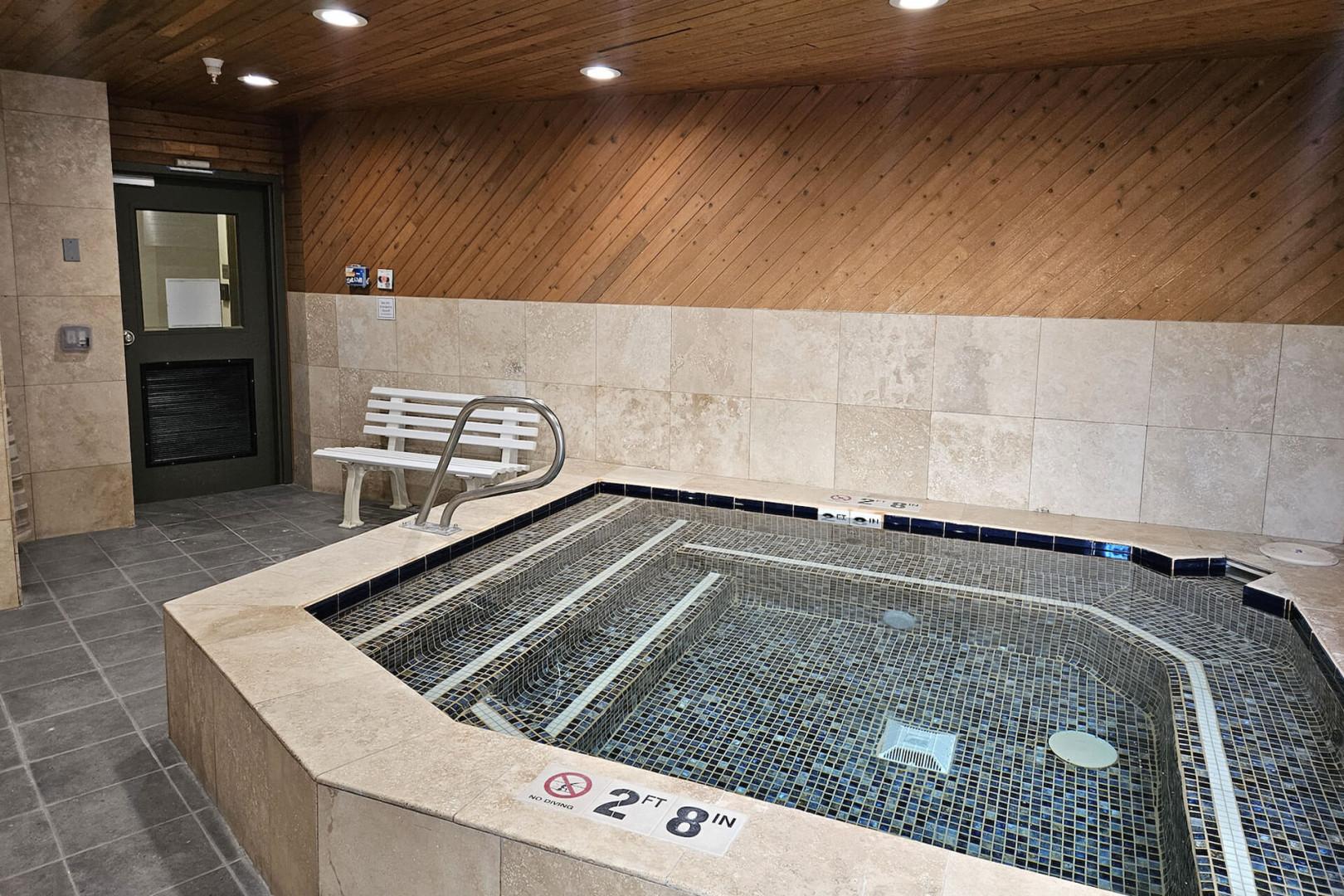 An indoor hot tub awaits with mosaic tile and warm wood accents, offering you a private retreat to soak away stress and unwind in comfort.