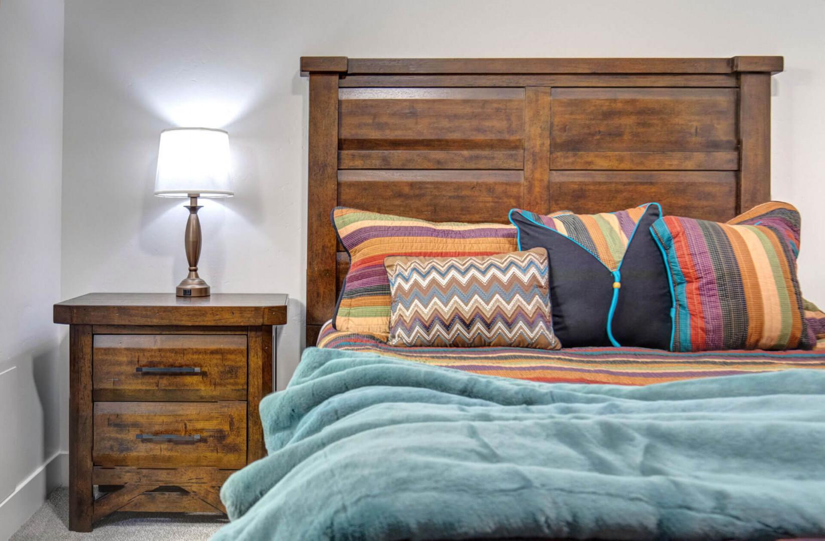 Sink into cozy comfort with this rustic wooden bed adorned with vibrant pillows and soft teal blankets—your perfect retreat awaits.