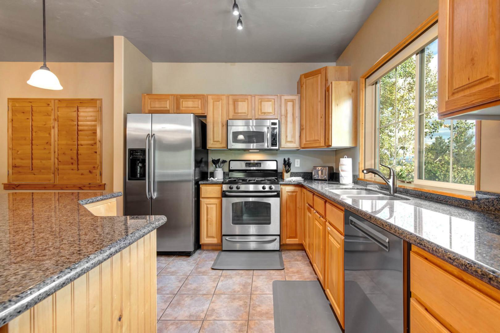 Cook memorable meals in this fully equipped kitchen featuring granite countertops, stainless steel appliances, and abundant natural light streaming through large windows.