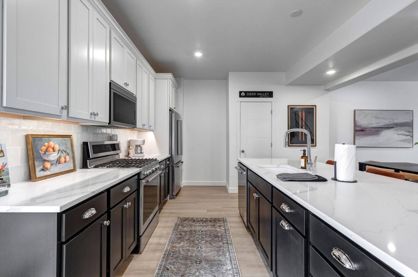 Your culinary dreams come alive in this stunning modern kitchen featuring pristine white countertops, premium appliances, and elegant two-tone cabinetry perfect for creating memorable meals.
