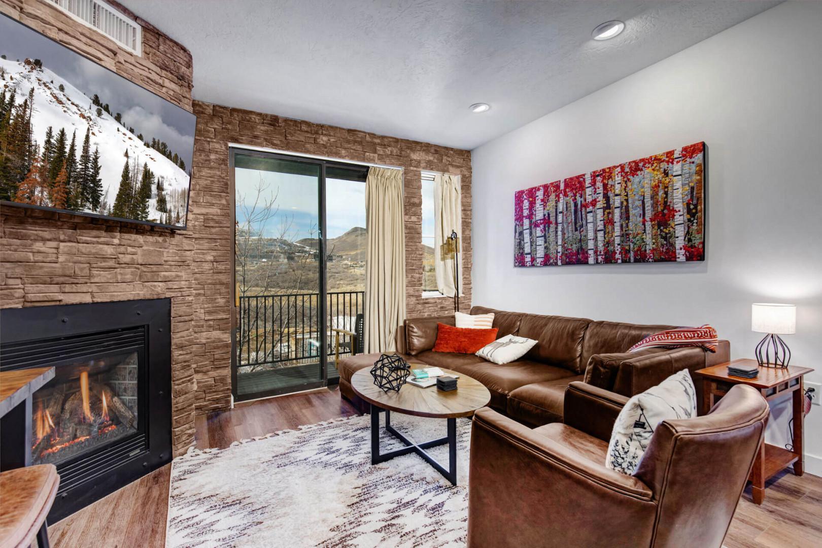 Unwind in your cozy living space with rich leather seating, crackling fireplace, and stunning mountain views through floor-to-ceiling windows.