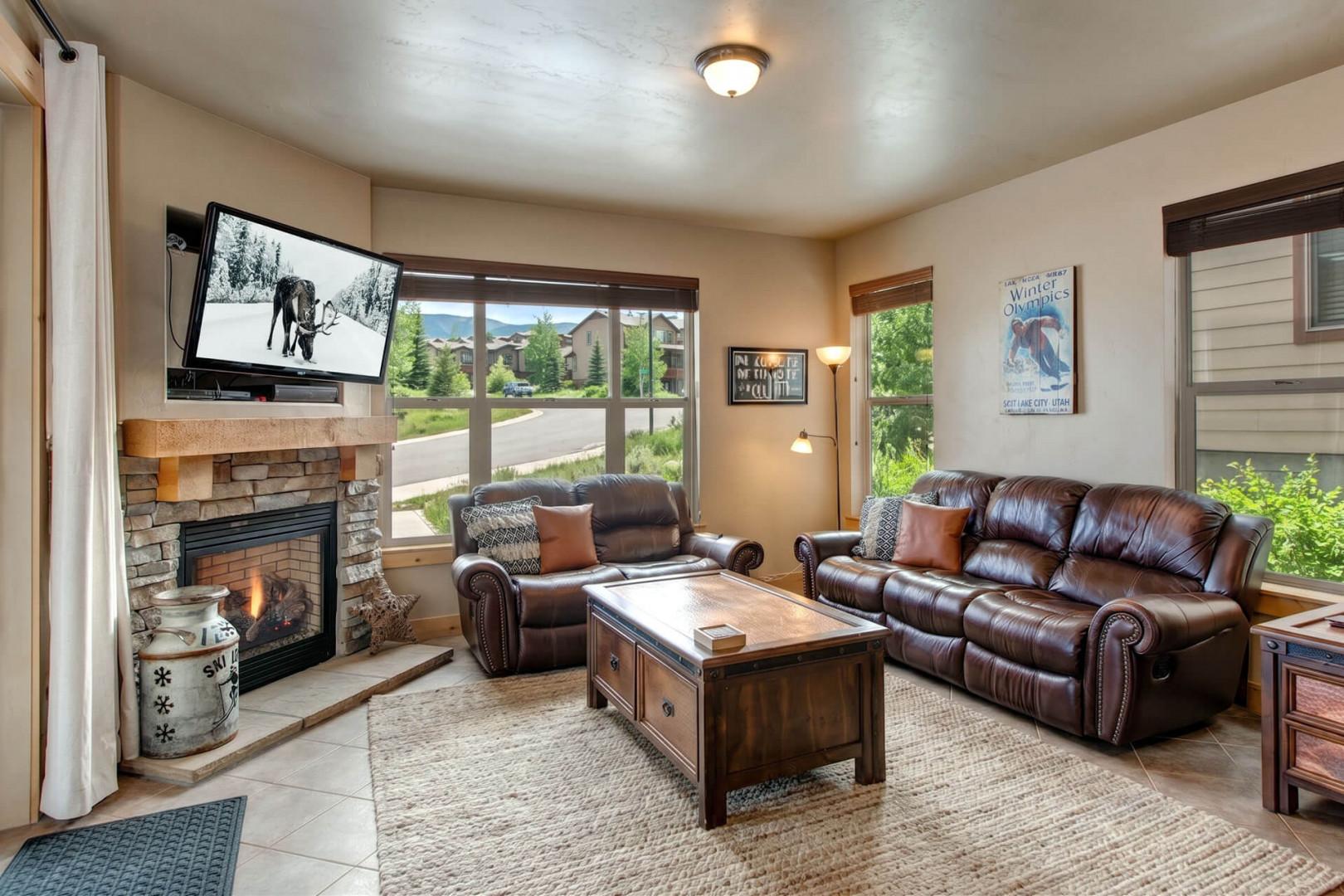 Sink into plush leather couches in your cozy living room, where a stone fireplace adds mountain charm and large windows frame peaceful neighborhood views.