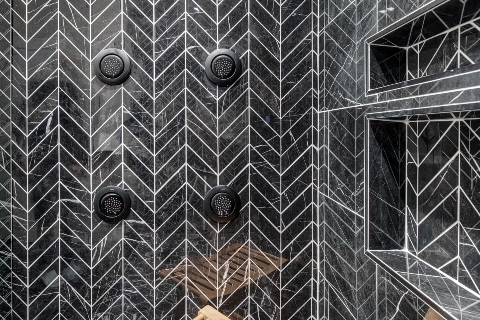 Upper Main 301: Your private spa awaits with stunning geometric marble walls and dual rainfall showerheads for a luxurious cleansing experience.