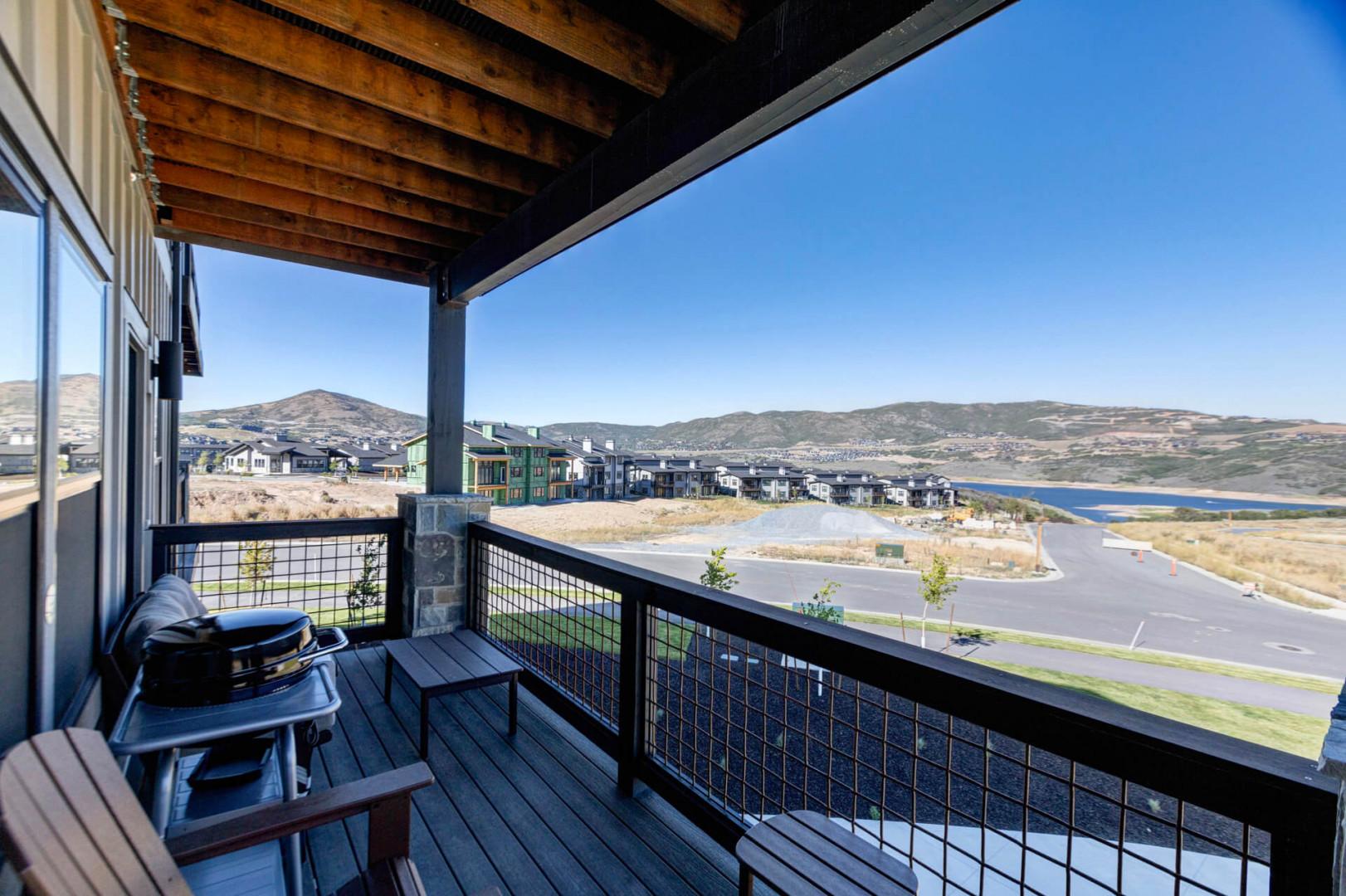 This covered balcony frames sweeping lake and mountain vistas under clear blue skies. Settle into the seating area and let the panoramic scenery become your backdrop for morning coffee or evening relaxation.