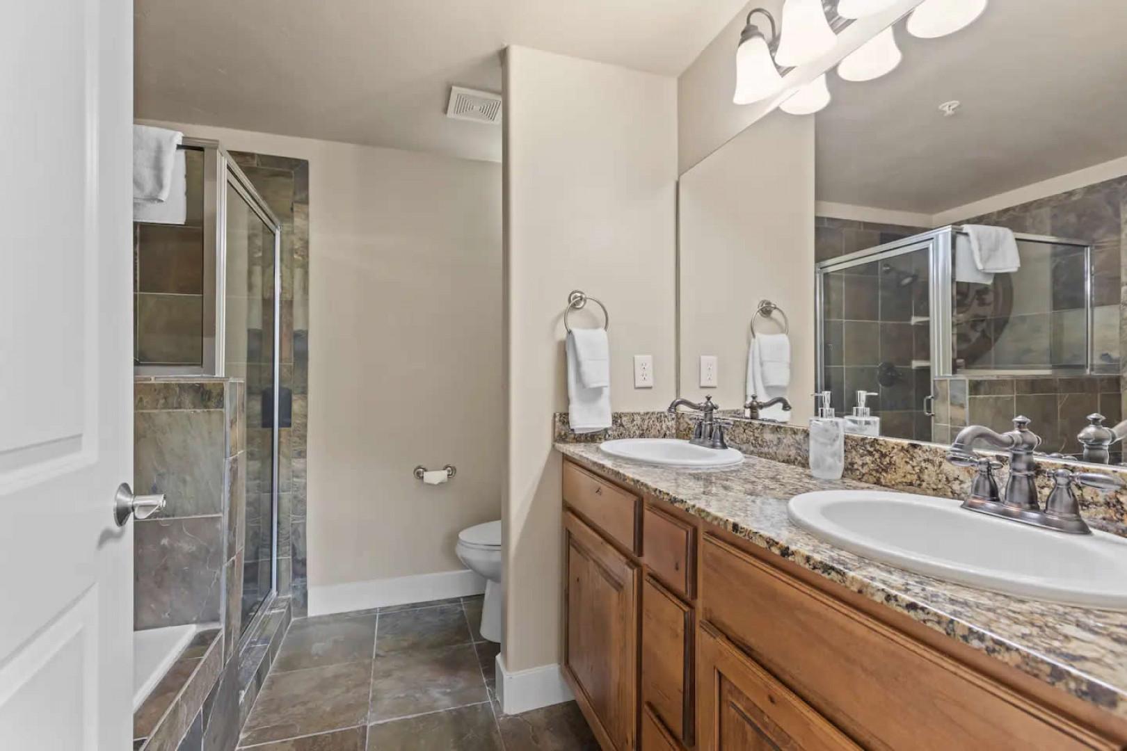 Sleek sink, mirror, toilet, and shower in modern design.