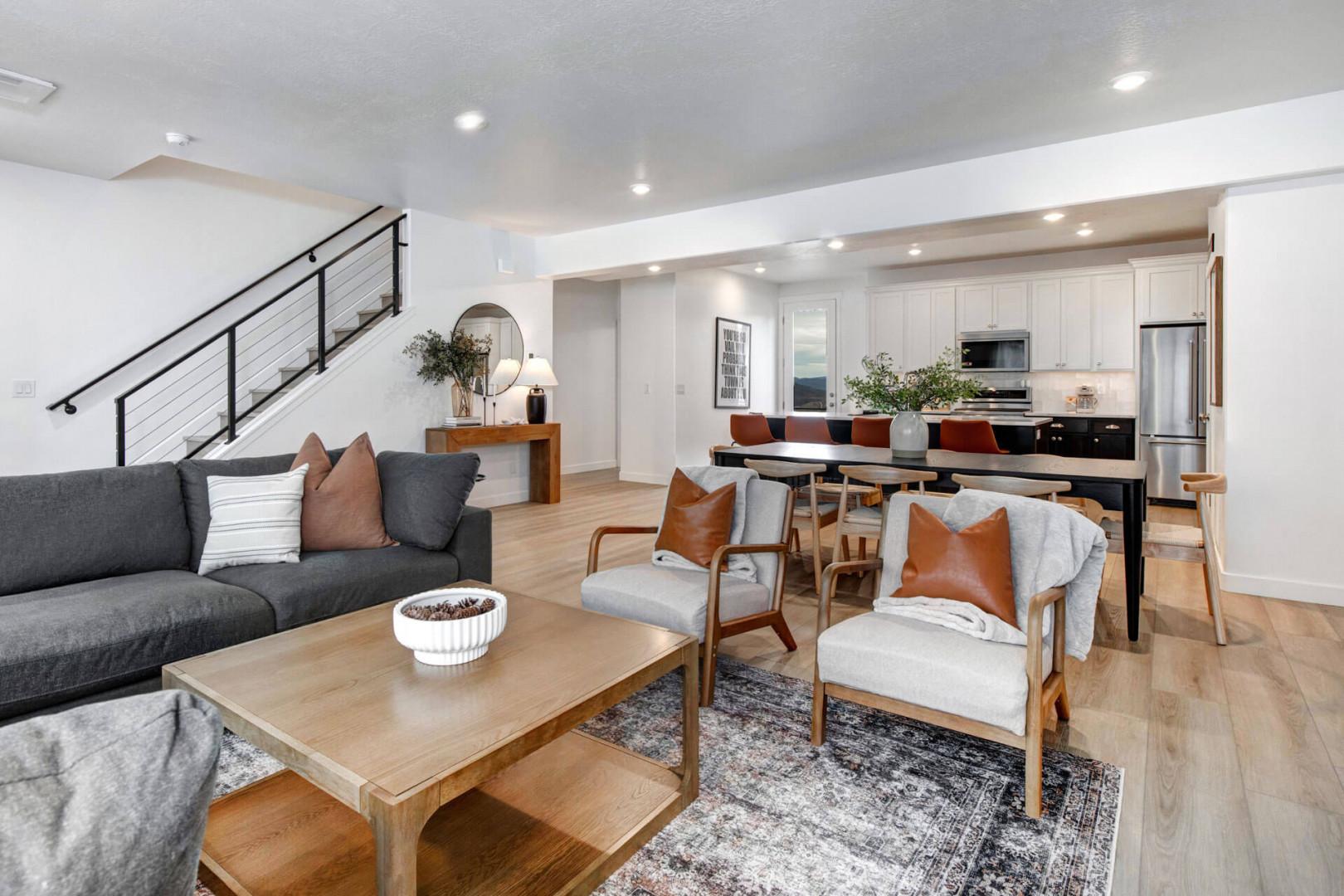 Relax in your stylish open-concept living space with modern furnishings, warm wood floors, and a fully equipped kitchen perfect for your stay.