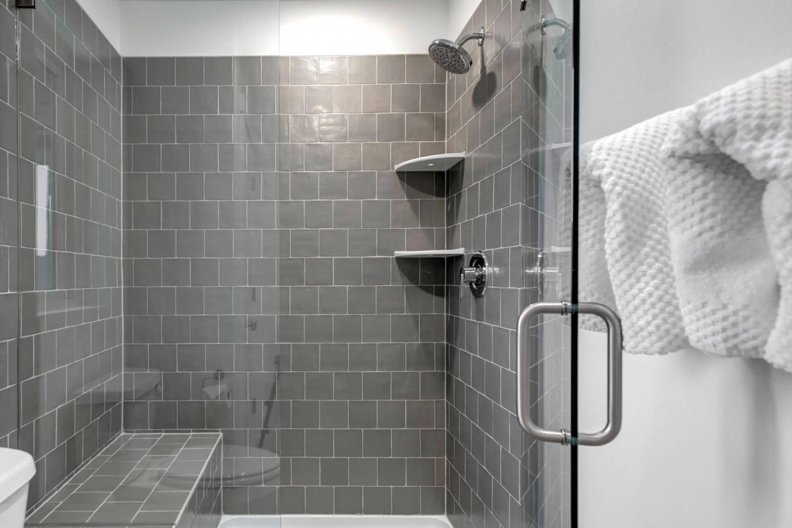 Step into your sleek glass-enclosed shower with beautiful gray subway tiles and rainfall showerhead for the perfect morning refresh.