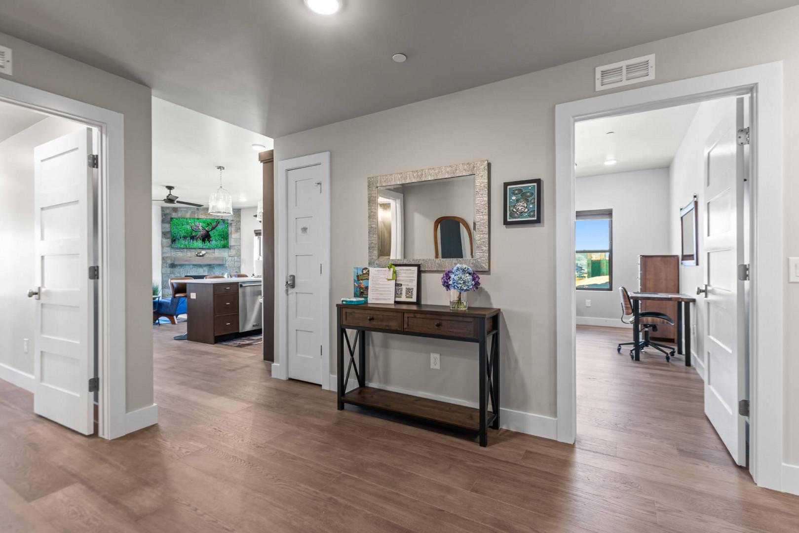 Your private hallway opens to inviting spaces throughout, from the bright living areas ahead to your personal office with a view on the right. Clean lines, warm wood floors, and thoughtful touches create a welcoming, connected home.